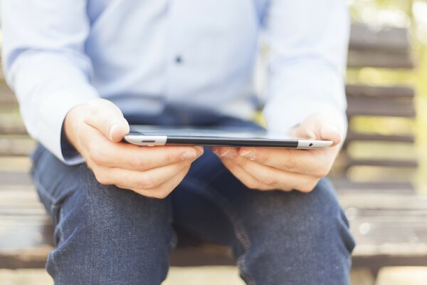 A man with a tablet on a bench in the park