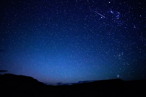 Cielo estrellado y meteoros en el fondo de las montañas