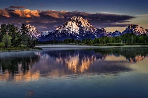 Montagnes enneigées. Lac. Nuages