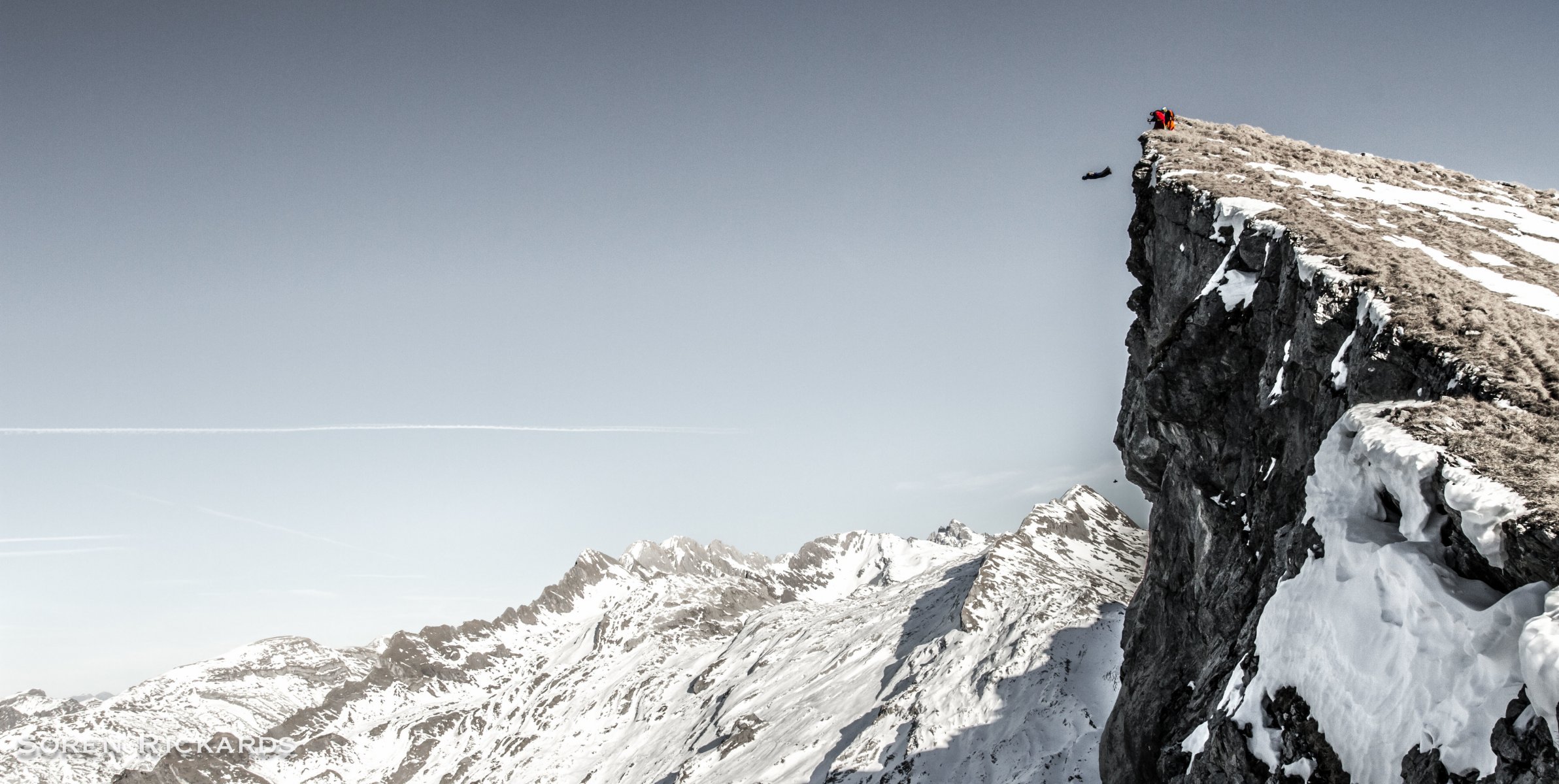 wingsuit pilot base jumping baser góry skały śnieg zima niebo szlak dymu kontener spadochron sporty ekstremalne