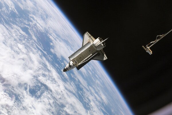 NASA shuttle hovers in space against the background of the earth