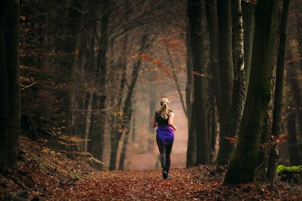 Une fille qui est sortie sur une course à travers la forêt d automne