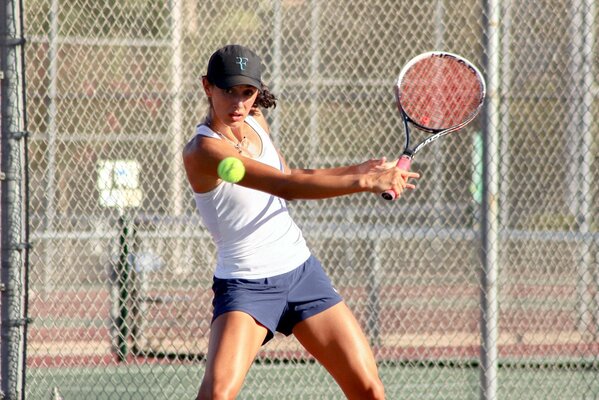 Mädchen mit Schläger schlägt einen Tennisball ab