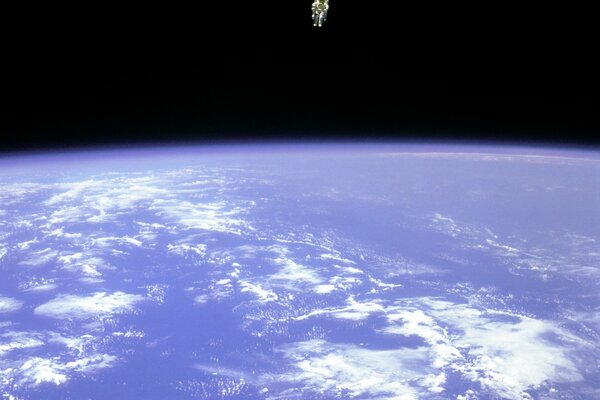 An astronaut above the Earth against the background of dark space