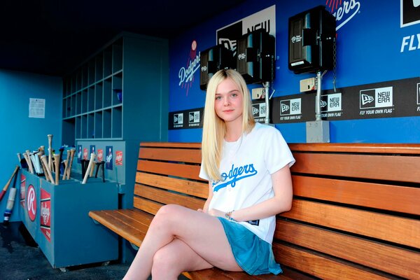 Elle Fanning is sitting on a bench