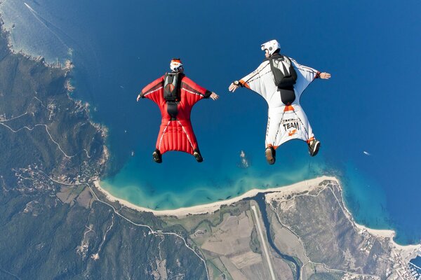 Wingsuits schweben über Strand und Meer