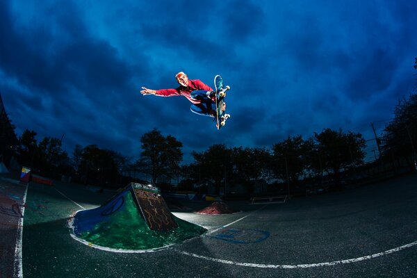 Salto in alto su uno skateboard sullo sfondo del cielo notturno