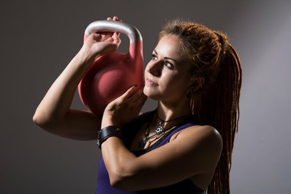 Rousse fille avec des dreadlocks et kettlebells