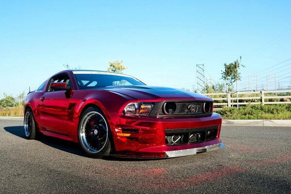 Das Auto ist ein roter Ford Mustang