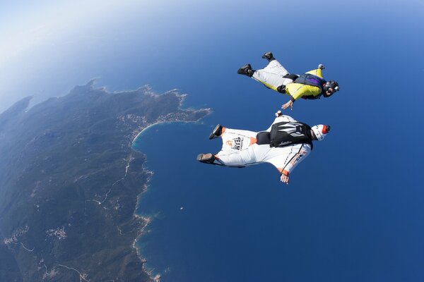 Zwei Wingsuits schweben über dem Meer