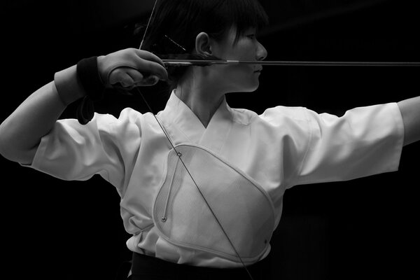 Fille japonaise en vêtements blancs tire un arc