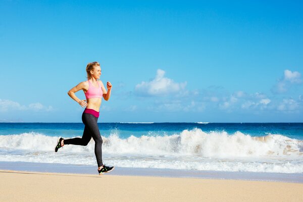 A sporty girl runs along a sandy beach