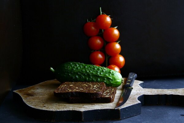 Essen auf einer Tafel mit einem Messer und Brot mit Gemüse, Tomaten und Gurken