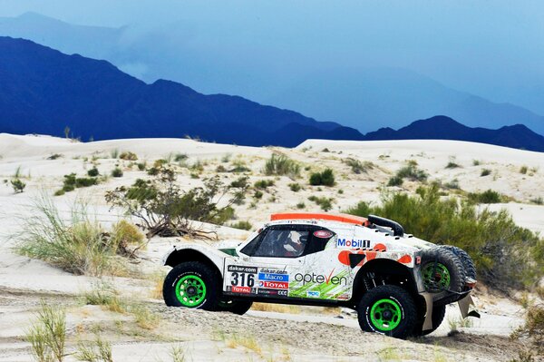 White buggy in the sand 2014 Dakar rally with green wheels