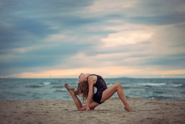 Graceful gymnastic pose on the sand