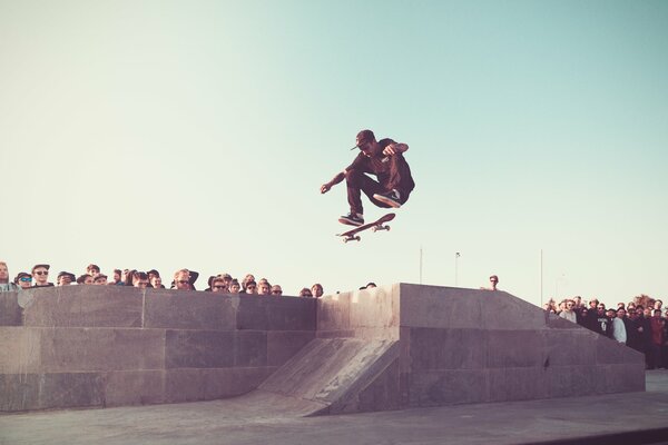 La folla guarda lo skateboarder fare il salto