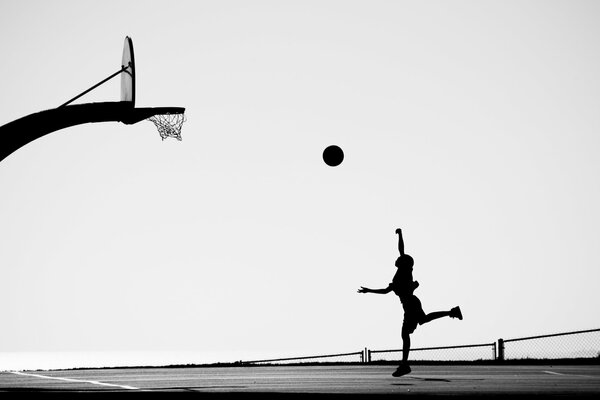 Silhouette eines Mädchens, das einen Ball in einen Ring wirft