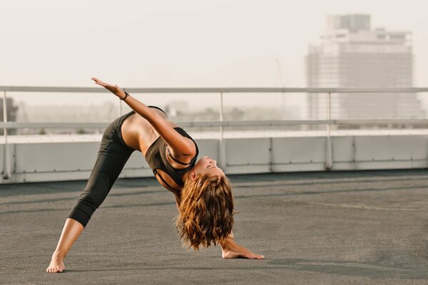 Ragazza che fa yoga sul tetto