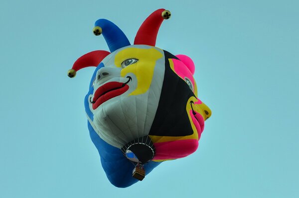 Bright balloon in the form of a clown on a blue background