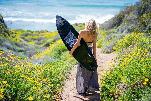 A girl with a surfboard on the seashore