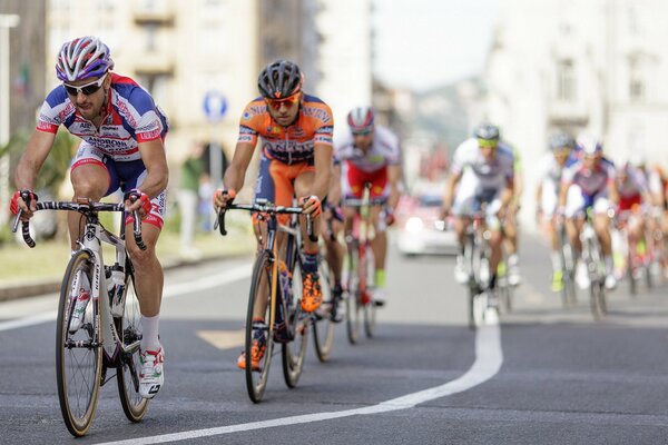 Wyścig rowerowy w mieście. Sportowcy rowerzyści tapety