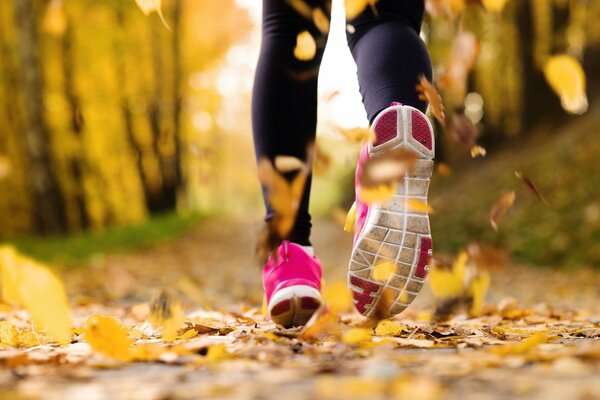 Uomo che corre lungo la strada autunnale in scarpe da ginnastica