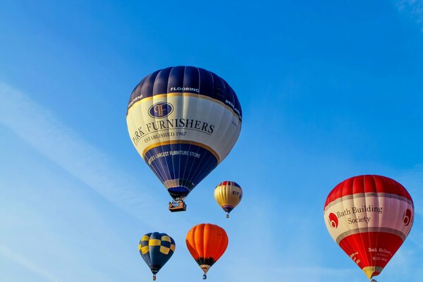 Cinq ballons colorés volent dans le ciel bleu