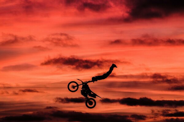 Stunt auf dem Hintergrund der roten Wolken auf einem Motorrad