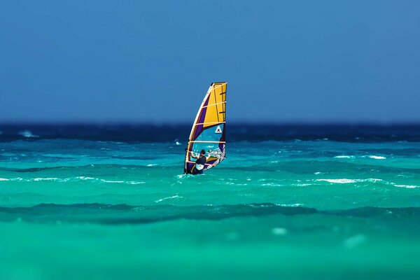 The wind carries the sailboat over the waves