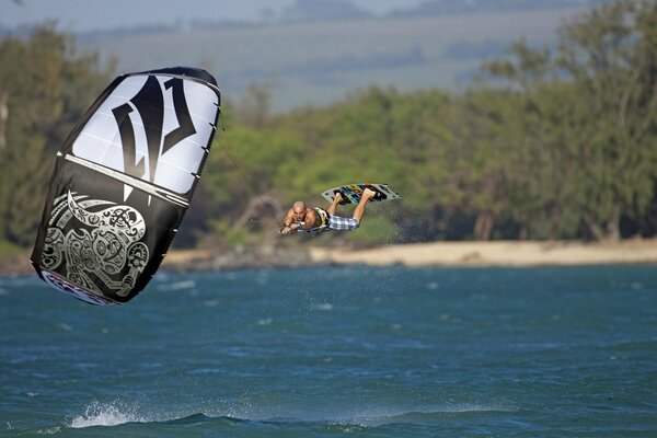 Surfeur vole au-dessus de la mer, tenant un parachute