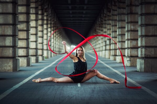 A gymnast girl with ribbons is sitting in a twine