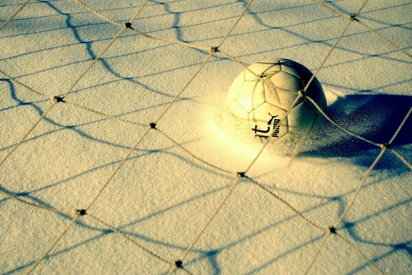 A ball on the sand under the net in yellow tones