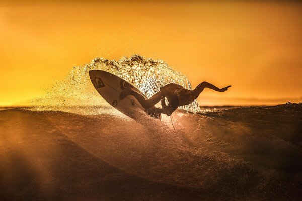 Surfing o zachodzie słońca sportowiec łapie falę