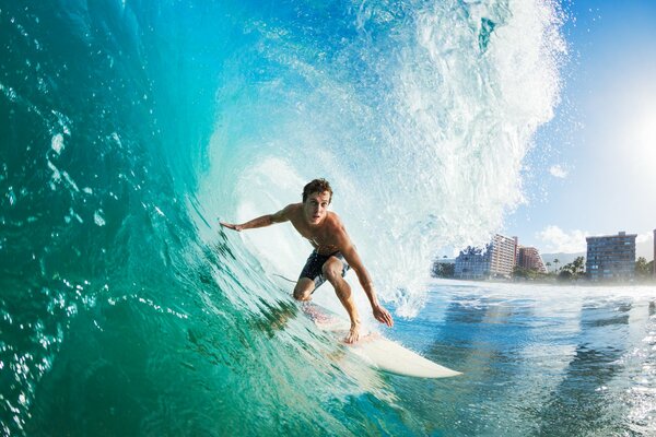 Ein Surfer, der eine Welle vor dem Hintergrund einer Stadt gefangen hat