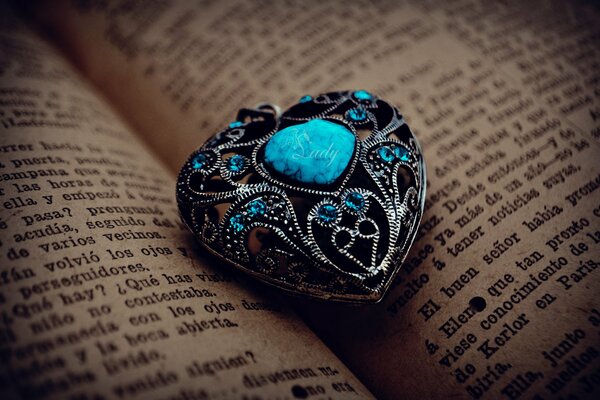 Turquoise stone in the form of a heart on the background of book pages