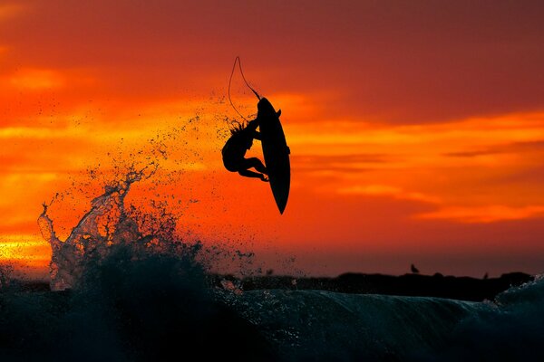 Surfer fliegt bei Sonnenuntergang eine Welle entlang