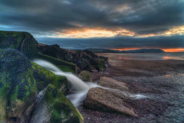 Landschaft am Meer Sonnenuntergang und grüne Steine