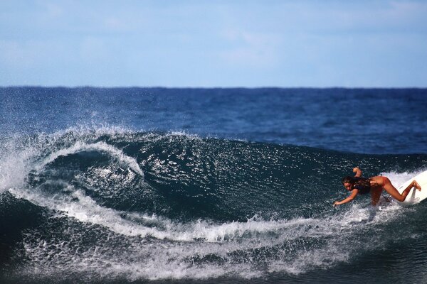 Chica de pie en una tabla de surf en una ola