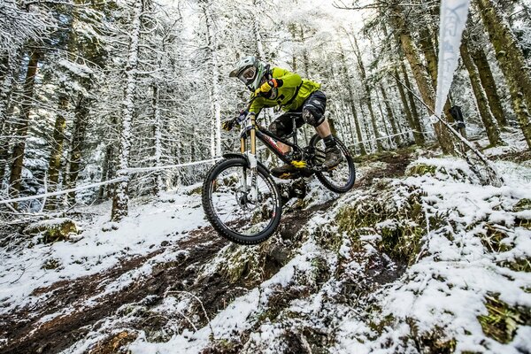 Mit dem Fahrrad von einem schneebedeckten Berg in Shorts