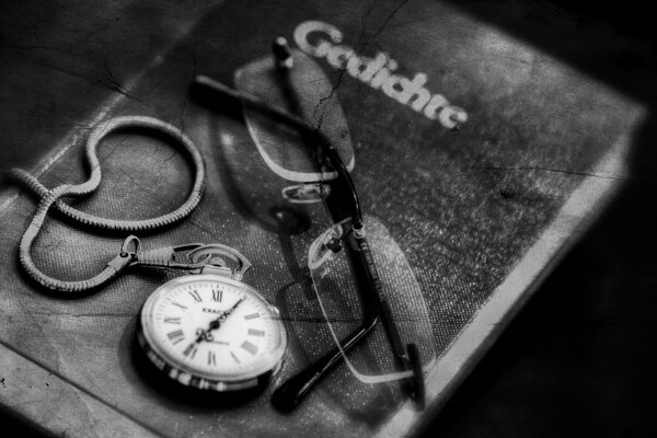 Montres et lunettes se trouvent sur le livre, noir et blanc