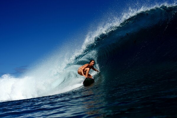 Fille sur une planche de surf conquiert la vague