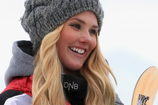 A girl with a snowboard in a gray hat