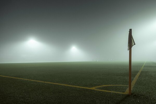 Campo de fútbol y bandera en la niebla