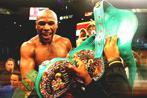 Joyful boxer Floyd Mayweather Jr., looking at the championship belts handed to him