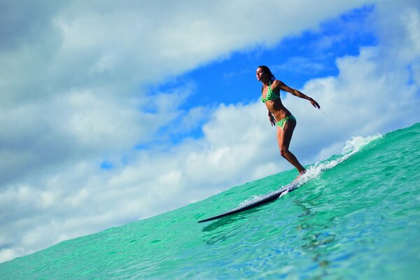 Surfer-Mädchen auf einem Brett auf dem Hintergrund von Meer und Himmel