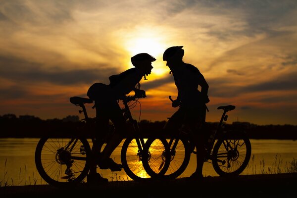 2 cyclistes sur fond de coucher de soleil et de la rivière