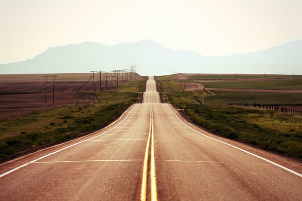 Longue route le long du champ directement dans les montagnes