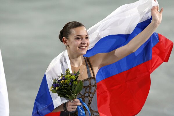 Sotnikova, die mit unserer Flagge auf einer Eisbahn mit einem Blumenstrauß umwickelt ist