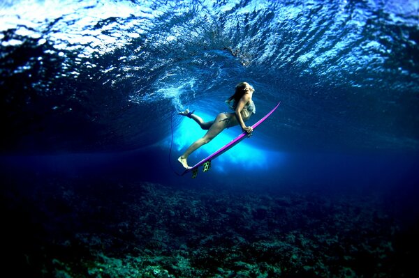 Chica surfista con una tabla bajo el agua