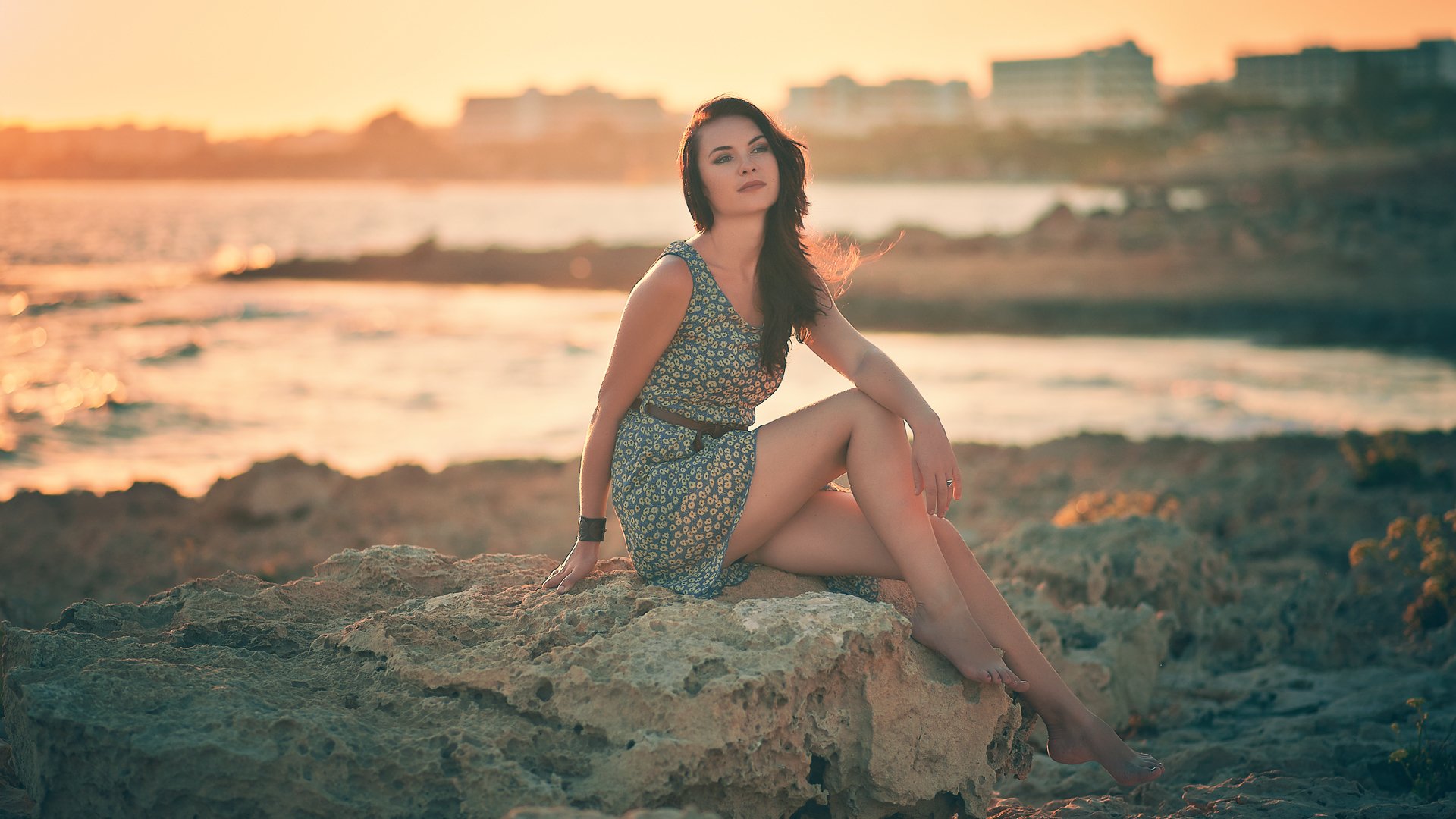 chica morena piedras orilla pose pulsera puesta de sol vista vestido